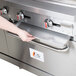 A hand inserting a stainless steel crumb tray into a stainless steel oven.