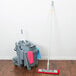 A Unger SmartColor mop and bucket on a wood floor.