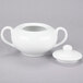 A 10 Strawberry Street Classic White porcelain sugar bowl with lid and spoon on a gray surface.