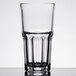 An Arcoroc stackable beverage glass filled with water on a white background.