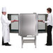 Two chefs standing in front of a Blodgett pass-through electric combi oven with a glass door.