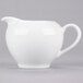 A white porcelain creamer with a handle.