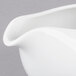 A close-up of a 10 Strawberry Street white porcelain gravy boat with a curved handle.