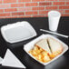 A white Dart foam container with a sandwich and chips inside.