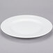 A white 10 Strawberry Street porcelain dinner plate with a rim on a gray surface.