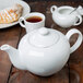 A white 10 Strawberry Street porcelain teapot and cups of tea on a table.