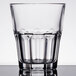 An Arcoroc tall rocks glass with a clear rim and a pattern on it.