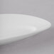 A close up of a white 10 Strawberry Street Ricard oval porcelain plate with a curved edge.
