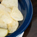 A Carlisle Dallas Ware cafe blue melamine plate with potato chips and a pickle.