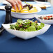 A white Fineline plastic serving bowl filled with salad on a table.