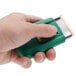 A hand holding a green Unger ErgoTec SafetyScraper with silver accents.