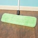 A green Lavex microfiber mop on a wood floor.