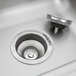 A close-up of the drain in a stainless steel Advance Tabco hand sink.
