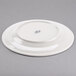 A white Tuxton Meridian china plate with an embossed swirl rim design.