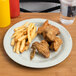 A Carlisle bone melamine plate with fried chicken and fries on it.
