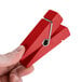 A hand holding a red American Metalcraft clothespin card holder.