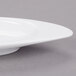 An Arcoroc white porcelain dish with a curved edge.