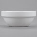 An Arcoroc porcelain stackable bowl with a small rim on a gray surface.