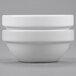 Two Arcoroc white porcelain stackable bowls sitting on a gray surface.