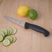 A Mercer Culinary Millennia 6" Utility Knife next to a lime and sliced limes on a table.
