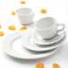 A Tuxton bright white china coupe saucer with an orange slice on it.