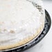 A coconut pie in a D&W Fine Pack black plastic container with a clear high dome lid.