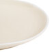 An Arcoroc sand porcelain plate with a small rim on a white surface.