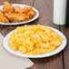 A white Bare by Solo medium weight paper plate with macaroni and cheese and chicken wings.