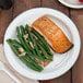 A Bare by Solo paper plate with a piece of salmon and green beans on a table.