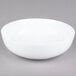 A CAC Bright White Porcelain salad bowl on a gray surface.