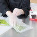 A person wearing gloves using an ARY VacMaster full mesh zipper bag to vacuum seal asparagus.
