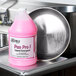 A pink bottle of Noble Chemical Pan Pro liquid detergent next to a sink in a professional kitchen.