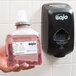 A hand using GOJO Premium Foam Hand Soap to refill a dispenser on a counter.