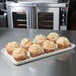 A MFG Tray Eggshell Fiberglass Supreme Display Tray of muffins on a counter.