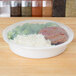 A white 48 oz. plastic round microwavable container with rice, broccoli, and meat in it.