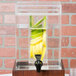 A Cal-Mil clear plastic beverage dispenser chamber with sliced fruit and lemon peels inside.