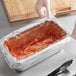 A person holding a plastic container with red sauce in it.