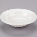 A Libbey ivory porcelain fruit bowl with a rim on a gray surface.