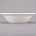 A Libbey ivory porcelain bowl with a round bottom on a gray surface.
