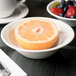 A Libbey ivory porcelain bowl filled with fruit including a half of a grapefruit and a half of an orange.