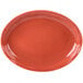 A red oval porcelain platter with a white wavy border.