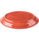 A red Libbey oval porcelain platter with a carved design on a table.
