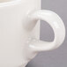 A close-up of a Libbey ivory porcelain stacking cup with a handle.