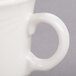 A close-up of a Libbey ivory porcelain tall tea cup with a handle.