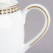 A white bone china tea pot with gold trim and a lid.