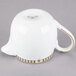 A white teapot with gold trim.