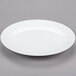 A Libbey Aluma White Porcelain coupe plate with a rim on a gray surface.