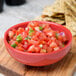 A red Libbey Cantina salsa bowl filled with salsa and chips.
