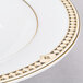 A close-up of a white Syracuse China Baroque bone china soup bowl with a gold design.