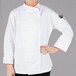 A woman wearing a white Mercer Culinary chef jacket with red piping.